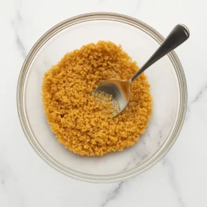 Graham cracker crust mixture in a glass bowl for Pina Colada Cheesecake Mousse