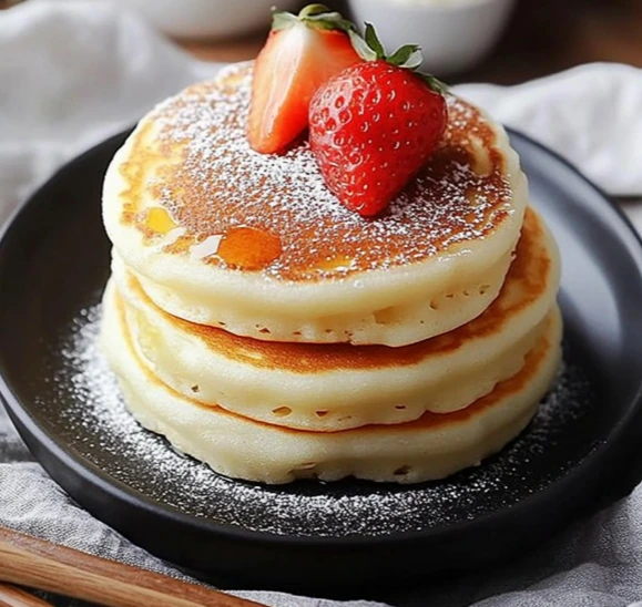 Stack of fluffy Japanese soufflé pancakes on a plate with berries