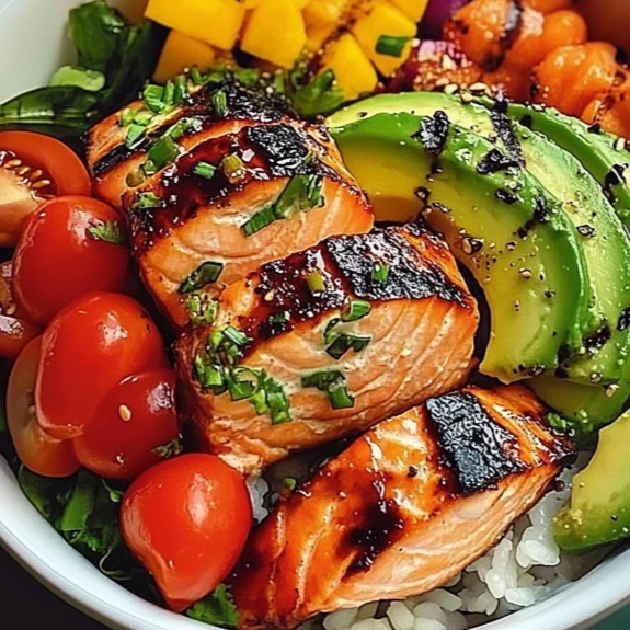 Bowl of grilled salmon with avocado, brown rice, and fresh veggies